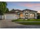 Charming single-Gathering home showcasing a well-manicured lawn, neutral paint, a two-car garage, and decorative architectural details at 701 Little Hampton Ln, Gotha, FL 34734