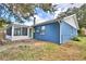 Exterior view of a blue house, showing its side, screened-in porch, and backyard area at 7504 Willow Wisp E Dr, Lakeland, FL 33810