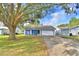 Charming single-story home with blue exterior, white trim, mature trees and a two-car garage on a sunny day at 7504 Willow Wisp E Dr, Lakeland, FL 33810