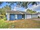 View of blue house with green tree, a driveway leading to a two-car garage, and a swing hanging from a branch at 7504 Willow Wisp E Dr, Lakeland, FL 33810