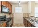 Kitchen area with wood cabinets, granite counters, tile flooring, and stainless steel sink at 909 Charo Pkwy # 1011, Davenport, FL 33897