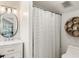 Well-lit bathroom featuring modern fixtures, decorative mirror, honeycomb shelving, and shower with patterned curtain at 9743 Chestnut Ridge Dr, Windermere, FL 34786