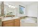 Bright bathroom featuring a soaking tub, double vanity, and large window at 10080 Cove Lake Dr, Orlando, FL 32836