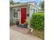 Home's entrance with a vibrant red door, potted plants, and manicured landscaping at 1021 N Forest Ave, Orlando, FL 32803