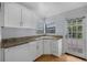 Well-lit kitchen equipped with granite countertops, white cabinets, and a convenient dishwasher at 1021 N Forest Ave, Orlando, FL 32803