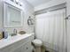 Neat bathroom featuring a white vanity, framed mirror, decorative shelving and a shower with a curtain at 10460 Riva Ridge Trl, Orlando, FL 32817