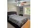 Cozy bedroom featuring a ceiling fan, woven headboard and built in shelving with a view to the outdoors at 1051 S Highland St # 5E, Mount Dora, FL 32757