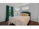 Cozy bedroom with hardwood floors, window with dark green curtains, and a comfortable bed at 13826 Mirror Lake Dr, Orlando, FL 32828