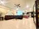 Open-concept living area flows into the kitchen with a dark leather sofa, tiled floors, and a ceiling fan at 16611 Toccoa Row, Winter Garden, FL 34787