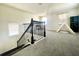 An upper loft space with carpet features black iron spindles and a decorative chandelier at 16611 Toccoa Row, Winter Garden, FL 34787