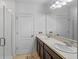 Bathroom featuring dual sinks, dark wood cabinets, neutral tile flooring, and glass-enclosed shower at 189 Luxmore Rd, Groveland, FL 34736