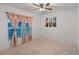 Bright bedroom with a ceiling fan, neutral carpet, and a large window with charming peach floral curtains at 189 Luxmore Rd, Groveland, FL 34736