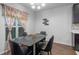 Modern dining room featuring a sleek black table, leather chairs, and bright window with decorative floral curtains at 189 Luxmore Rd, Groveland, FL 34736