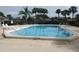 Community pool surrounded by palm trees, lounge chairs, and a secure fence for residents' enjoyment at 2002 Cascades Blvd # 201, Kissimmee, FL 34741