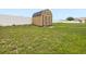 Backyard shed surrounded by green grass and a white privacy fence, offers storage at 204 Cotswold Cir, Davenport, FL 33837
