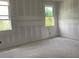 Unfinished bedroom features two windows letting in natural light, taped drywall ready for paint and flooring at 2379 Broadbrook Drive, St Cloud, FL 34771
