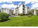 Exterior view of a white condo building featuring lush landscaping, palm trees, and grassy area at 300 Carolina Ave # 205, Winter Park, FL 32789