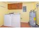 Laundry room with washer, dryer, water heater, wood cabinets, and tile floor at 300 Carolina Ave # 205, Winter Park, FL 32789