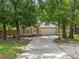 Single-story home featuring lush trees, a two-car garage, and a long driveway, providing ample parking space at 30926 County Road 435, Sorrento, FL 32776