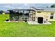 Back of property with screened pool area, solar panels, and lush green grass at 318 Langham Dr, Davenport, FL 33897