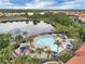 Aerial view of a community pool with lounge chairs, a hot tub, lake views, and tropical landscaping at 391 Cabello Dr, Davenport, FL 33837