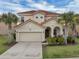 Two-story home with a red tile roof, a two car garage, palm trees, and manicured landscaping at 391 Cabello Dr, Davenport, FL 33837