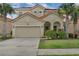 Charming two-story home featuring a red tile roof, a two-car garage, and tropical landscaping at 391 Cabello Dr, Davenport, FL 33837