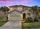 Charming two-story home featuring a red tile roof, an attached two-car garage, and tropical landscaping at 391 Cabello Dr, Davenport, FL 33837