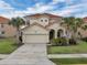 Inviting two-story home showcasing a red tile roof, tropical landscaping, and an attached two-car garage at 391 Cabello Dr, Davenport, FL 33837