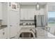 Close-up of a modern kitchen featuring white cabinetry, and stainless steel appliances at 394 Quayside Ave, Mascotte, FL 34753