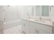 Bright bathroom featuring marble accent wall, shower, and double vanity with white cabinets and quartz countertop at 404 Famagusta Dr, Davenport, FL 33896