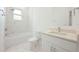 Clean, all-white bathroom featuring marble accents, a shower-tub combo, and a modern sink vanity at 404 Famagusta Dr, Davenport, FL 33896