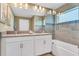 Well-lit bathroom featuring a double vanity with white cabinetry and a glass-enclosed shower-tub combo at 424 Ocean Course Ave, Davenport, FL 33896