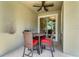 A cozy outdoor patio with ceiling fan, table, and four chairs with red cushions at 424 Ocean Course Ave, Davenport, FL 33896