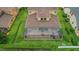 Aerial view of the home featuring a large screened lanai and well-maintained yard enclosed by a black fence at 4265 Foxhound Dr, Clermont, FL 34711