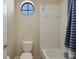 Bathroom with a round window, tiled walls, bathtub and shower with blue striped curtain at 4265 Foxhound Dr, Clermont, FL 34711