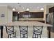 A modern kitchen features dark cabinets, a large center island with stone countertops, and stainless steel appliances at 4265 Foxhound Dr, Clermont, FL 34711