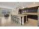 Spacious kitchen featuring dark wood cabinetry, a large granite island with seating, and stainless steel appliances at 4265 Foxhound Dr, Clermont, FL 34711