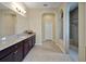A spacious main bathroom with granite countertops, dark wood cabinets, walk-in shower, and tile floors at 4265 Foxhound Dr, Clermont, FL 34711