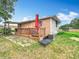 Back exterior of home with wood deck, seating area, and well-manicured lawn and red umbrella at 516 Petes Ln, Davenport, FL 33837