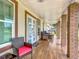 Inviting covered front porch featuring wood tile floors and brick columns offers a cozy outdoor seating area at 516 Petes Ln, Davenport, FL 33837