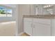 Bright bathroom featuring a granite countertop vanity and neutral walls that leads into a carpeted bedroom with a sunny window at 928 Pearlwood Loop, Eagle Lake, FL 33839