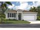 Charming single-story home featuring a two-car garage, front yard, and tropical landscaping at 928 Pearlwood Loop, Eagle Lake, FL 33839
