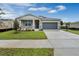 Inviting one-story home with a gray door, stone accents, and a well-maintained lawn under a bright, partly cloudy sky at 928 Pearlwood Loop, Eagle Lake, FL 33839