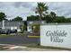 Community sign for Golfside Villas with building exteriors and mature palm trees at 1000 S Semoran Blvd # 608, Winter Park, FL 32792