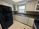Kitchen featuring white cabinets, black appliances, a double sink, and tile floors at 1000 S Semoran Blvd # 608, Winter Park, FL 32792