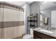 Neutral-toned bathroom with granite vanity, decorative shelving and a striped shower curtain at 10078 Hampshire Oaks Dr, Orlando, FL 32825