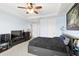 Bedroom with soft blue walls and carpet flooring, featuring a black bed frame, ceiling fan, and TV at 10308 Belfry Cir, Orlando, FL 32832
