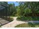 Landscaped backyard with a meandering stone path, screen enclosure, and mature trees with green grass at 140 Seville Chase Dr, Winter Springs, FL 32708