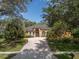 Inviting home featuring a brick driveway, lush landscaping, and an arched entryway set beneath mature trees at 140 Seville Chase Dr, Winter Springs, FL 32708